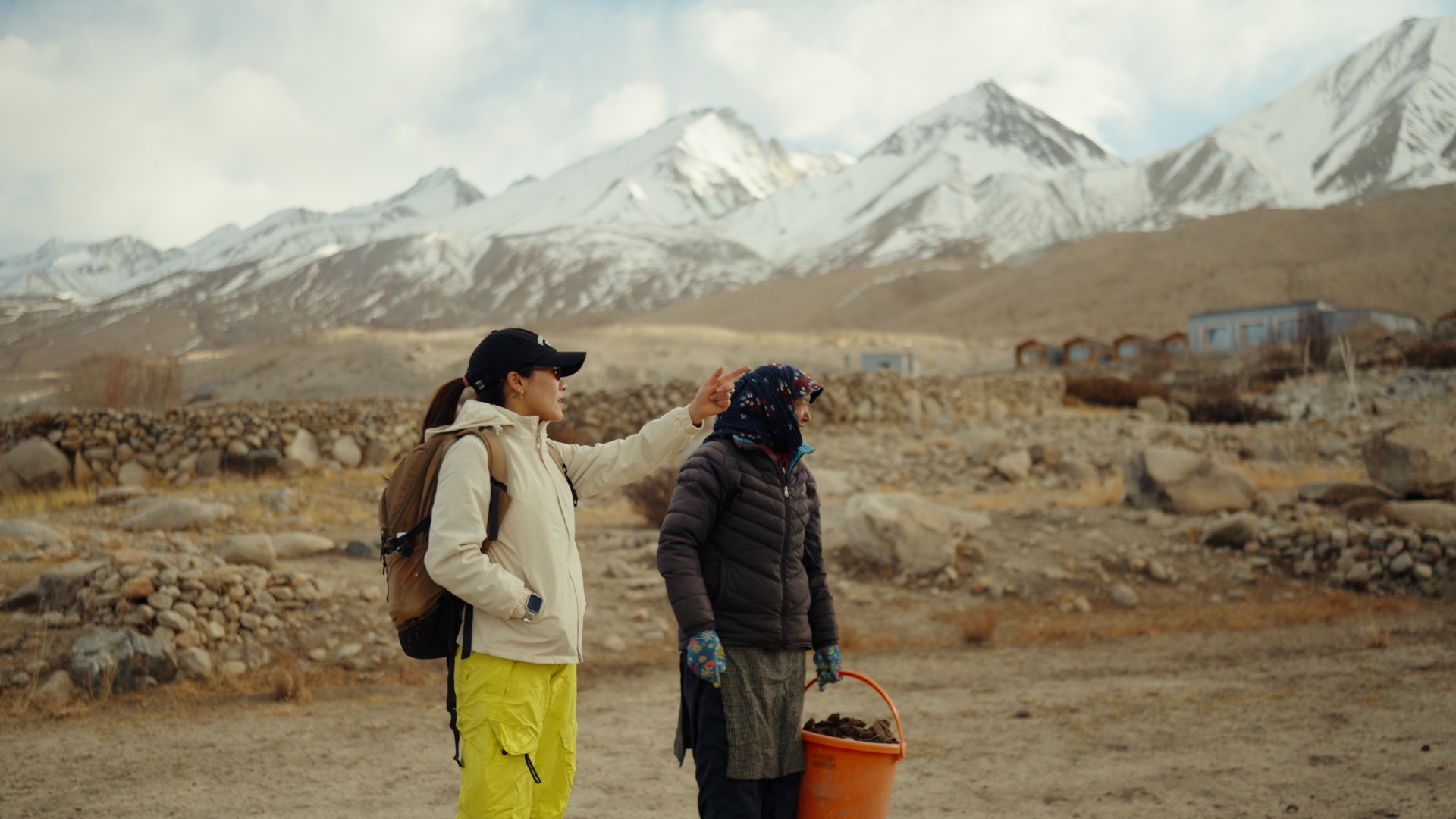 Stanzin pointing toward the mountains with a Pangong village local beside her