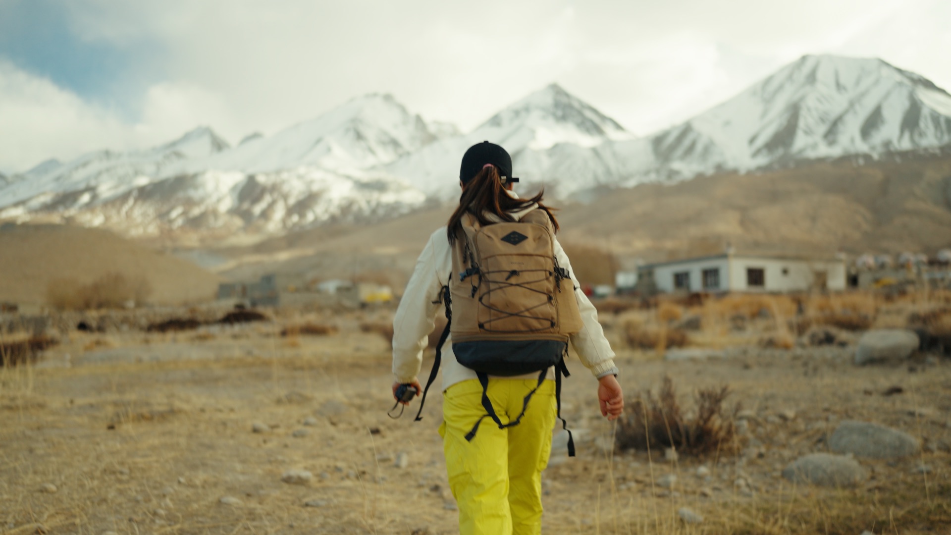 Stanzin hiking toward dramatic snow-capped Ladakhi peaks across open plateau